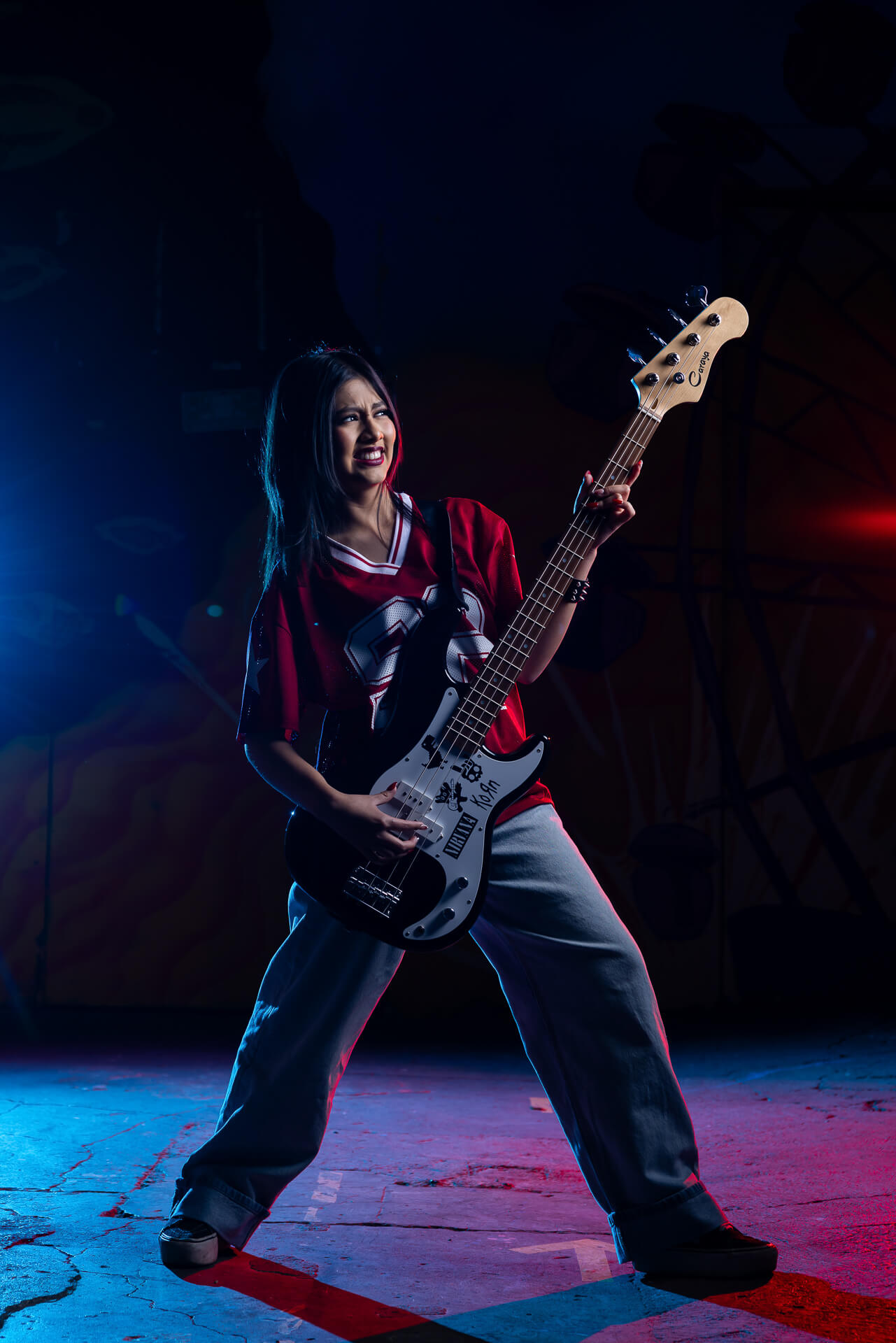 Retrato artístico de quinceañera con iluminación creativa azul y roja en entorno urbano.