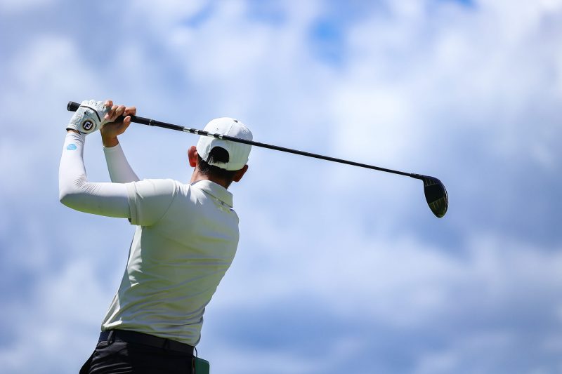 Detalle de la extensión de brazos en swing de golf profesional masculino.