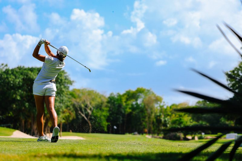 Jugadora de golf ejecutando un drive potente en el club de golf El Camaleón.