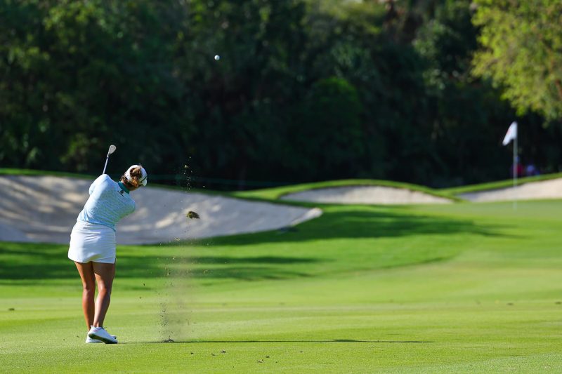 Jugadora de golf realizando un golpe de approach en el campo El Camaleón, Mayakoba.