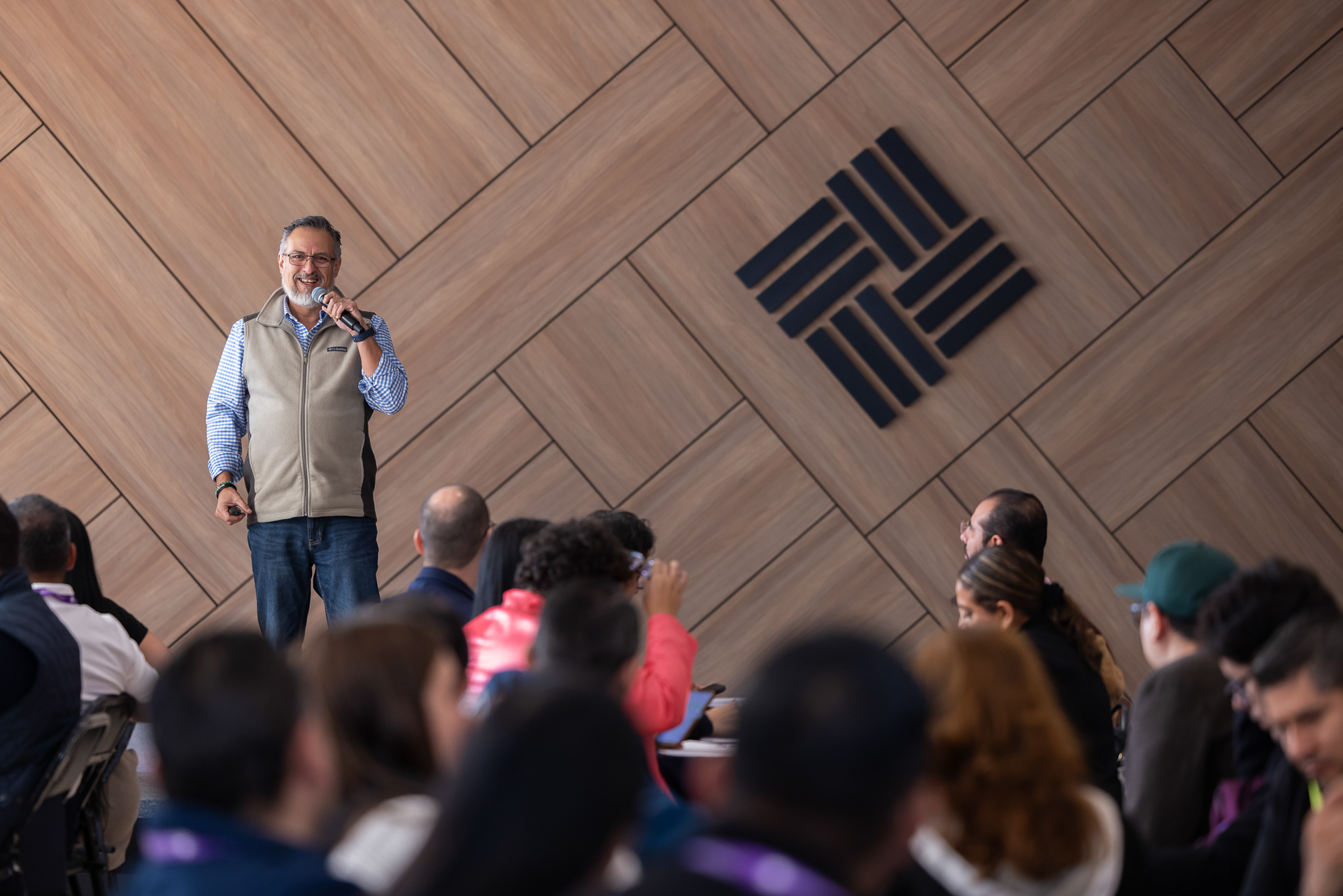 Ponente dando conferencia con logotipo de marca resaltado mediante cobertura audiovisual para eventos corporativos.