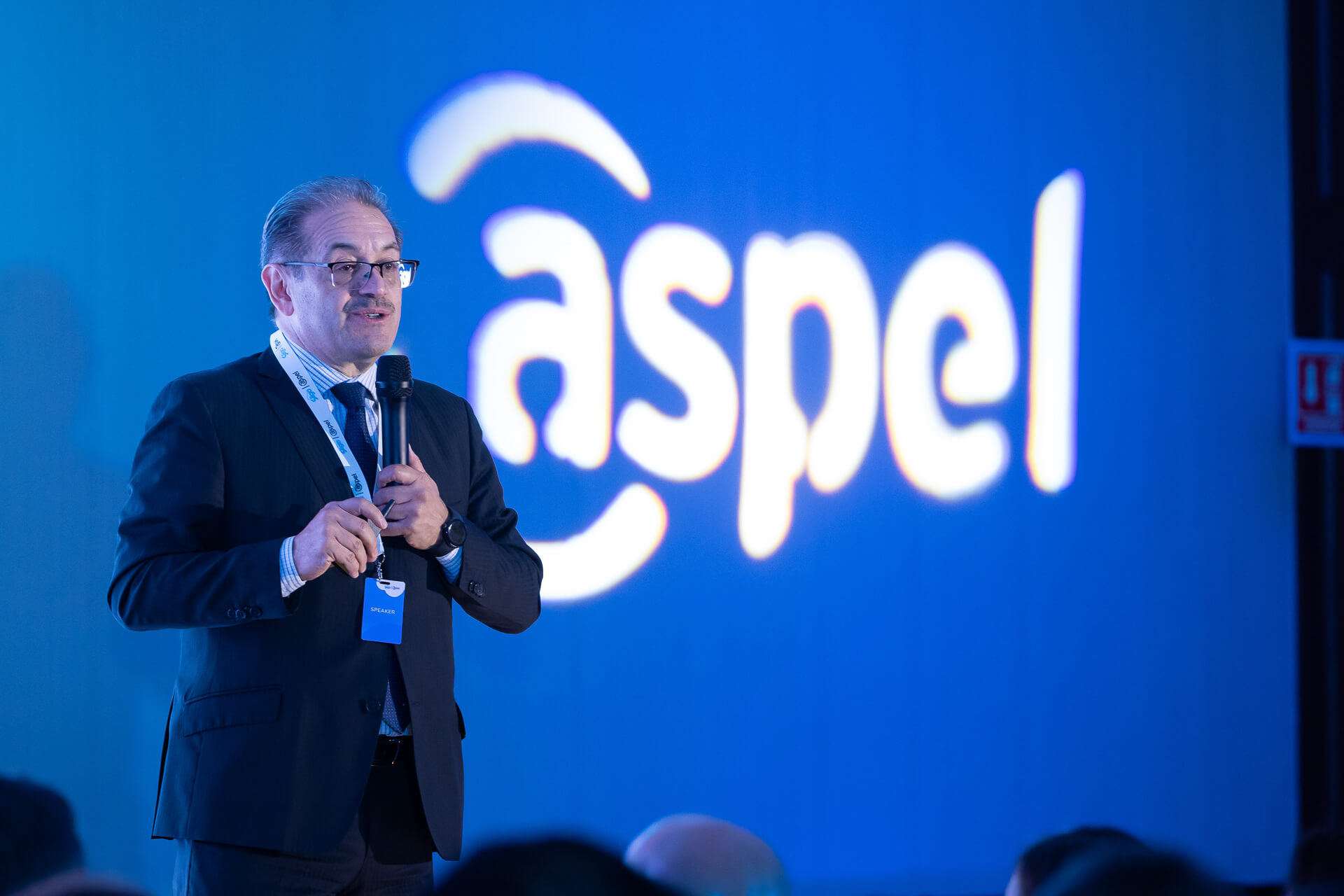 Ponente dando conferencia con logotipo de marca resaltado mediante cobertura audiovisual para eventos corporativos.