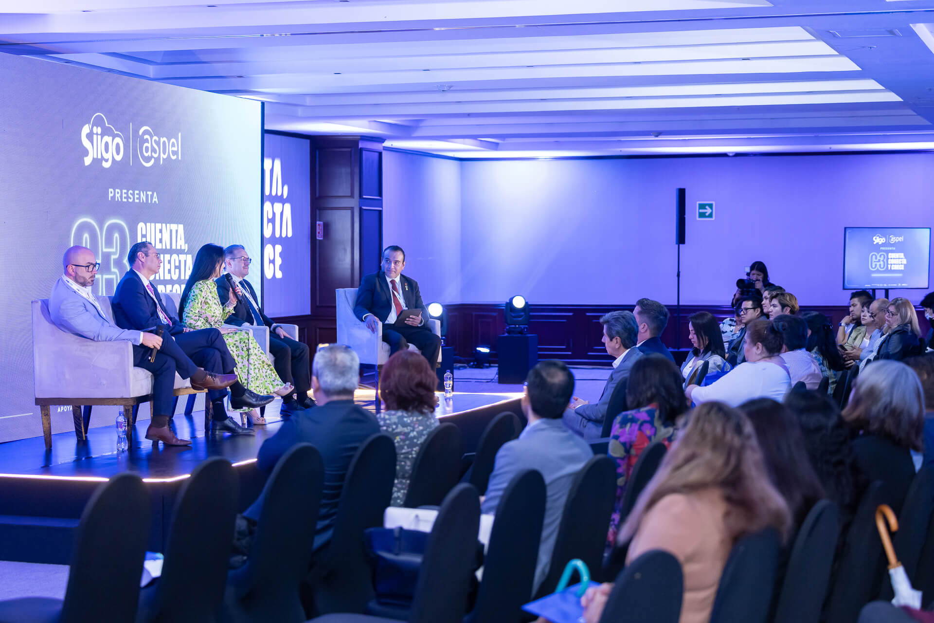 Panel de expertos en escenario durante una cobertura audiovisual para eventos corporativos integral.